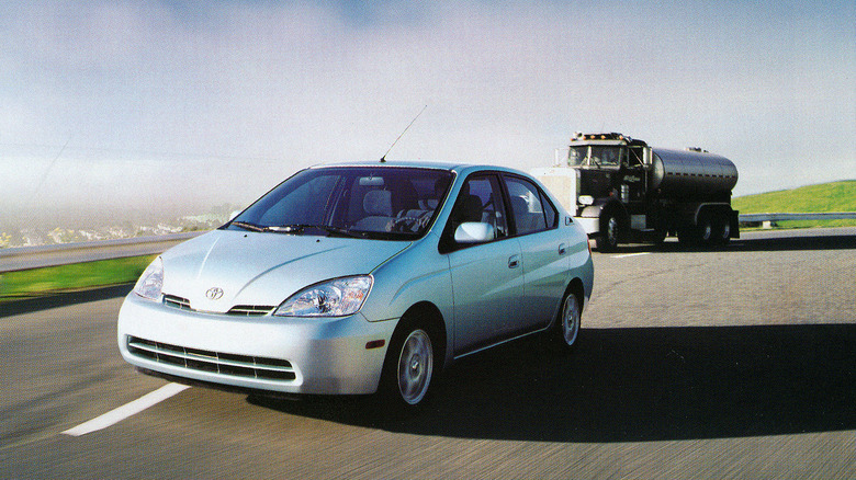 Silver Toyota Prius driving on highway in front of tanker truck