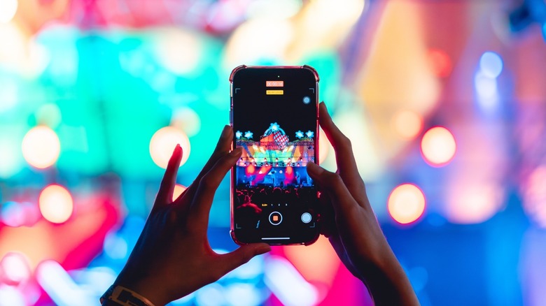 Person recording a video on a phone at a concert