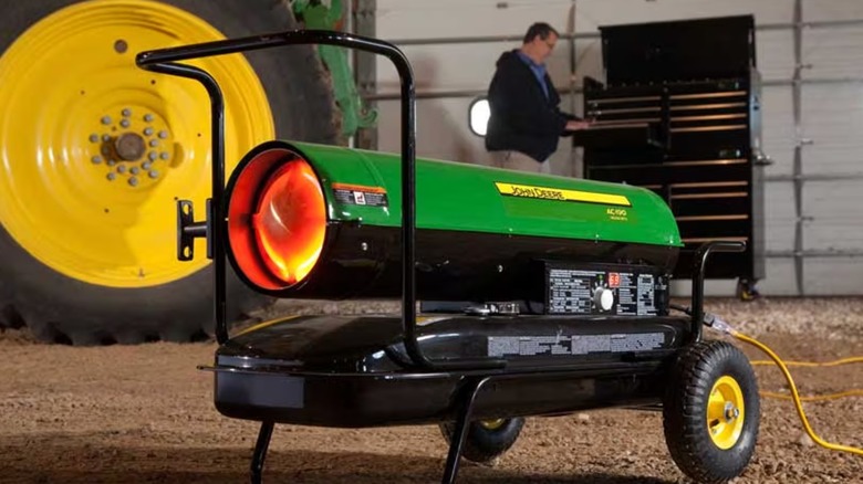 A John Deere jobsite heater with a worker in the background