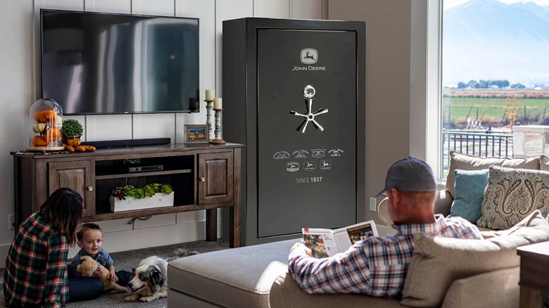 A man sits on a sofa in front of John Deere storage safe with a boy, woman and dog on the floor in front of him