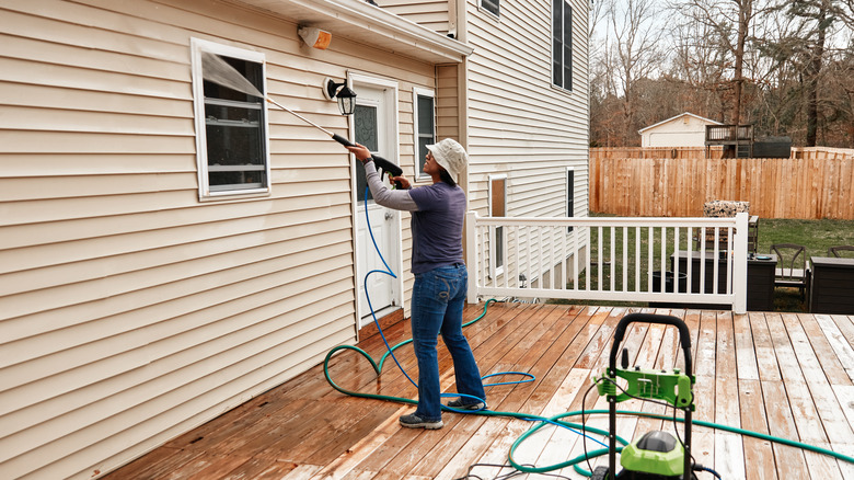 Person cleaning house with pressure washer