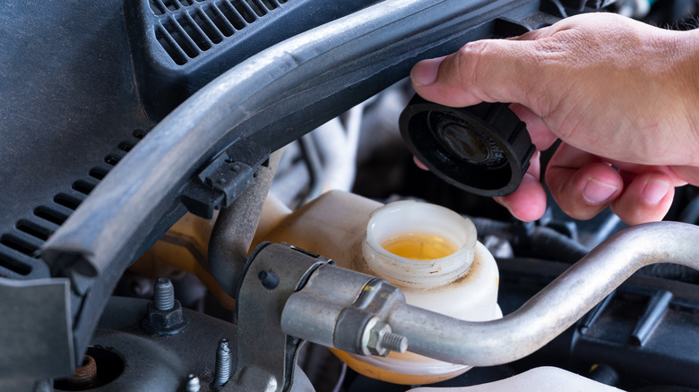 Auto mechanic checking brake fluid