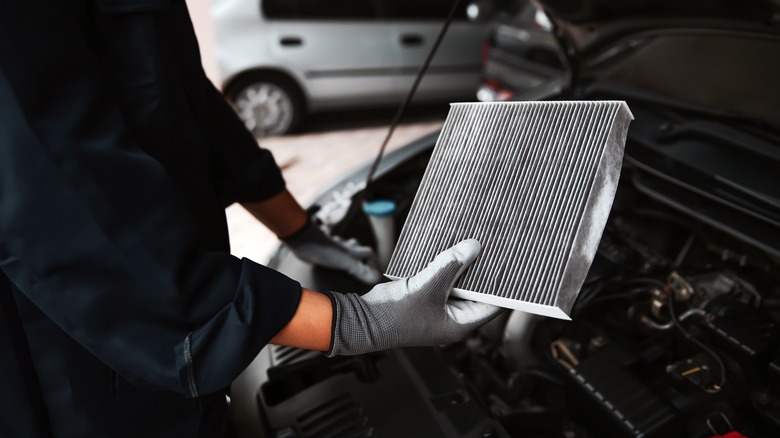 Auto mechanic holding air filter