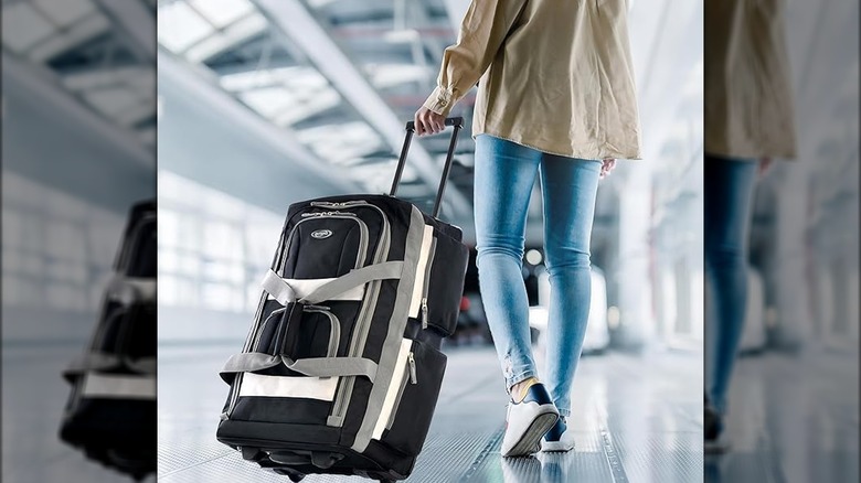 A woman rolls the water resistant olympia duffel bag in an airport