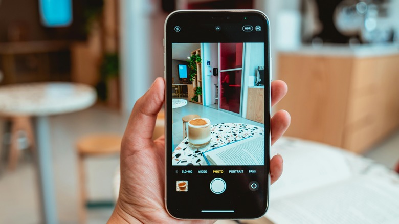 person holding iPhone towards a cafe