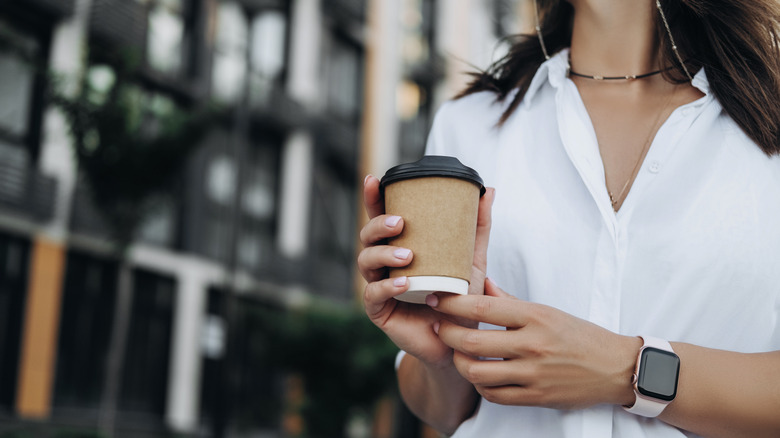 woman walking with coffee wearing an Apple Watch