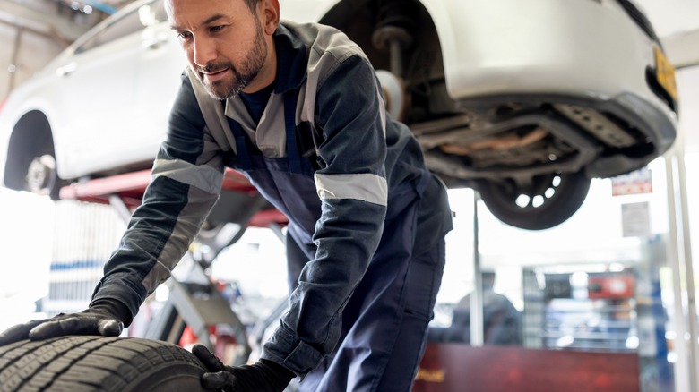 Mechanic wheeling a tire away