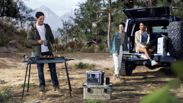 people camping while cooking and hanging Jeep using an Anker power station