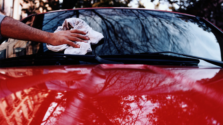 Man cleaning windshield of car