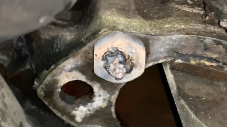 A nut welded onto a broken bolt on a thermostat housing on an engine