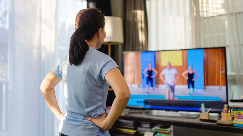 Woman following exercise instructors on TV