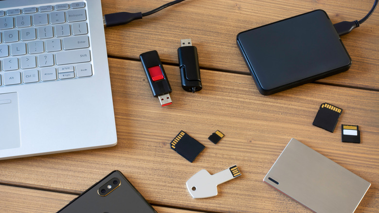 A laptop and a few storage devices on a wooden table