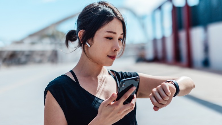 Woman with AirPods looking at her fitness tracker