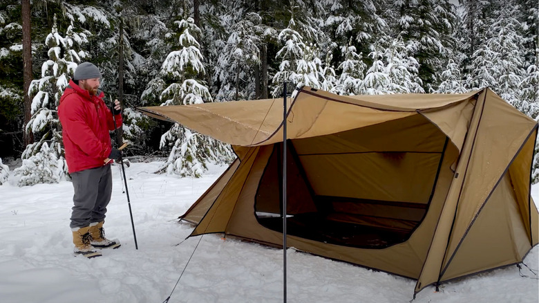 Man setting up tent in snow