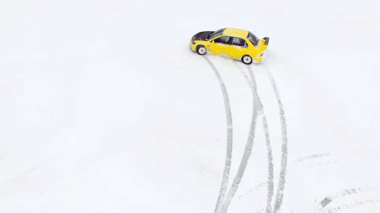 Yellow sports car on snowy frozen lake with tracks from skid