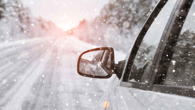 View of car's side-view mirror as it drives through moderately heavy snowfall