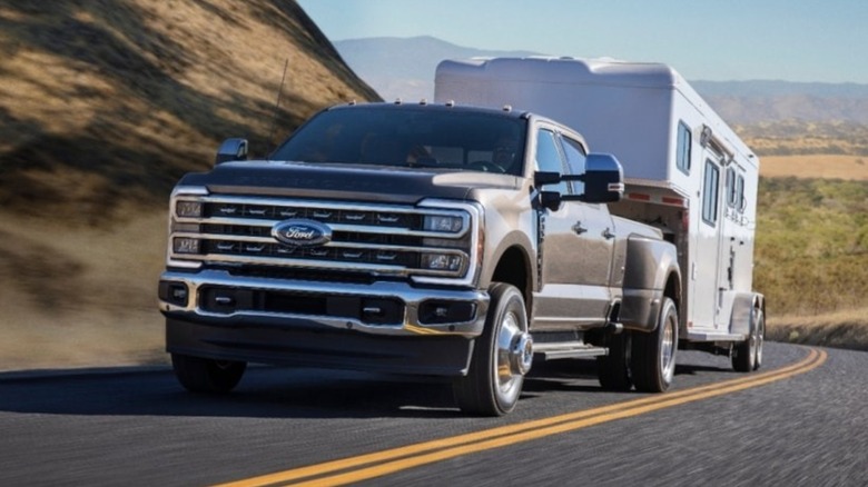 A Ford Super Duty towing a stock trailer through the mountains.