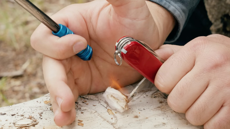 Man using Swiss Army Knife sewing awl to make fire