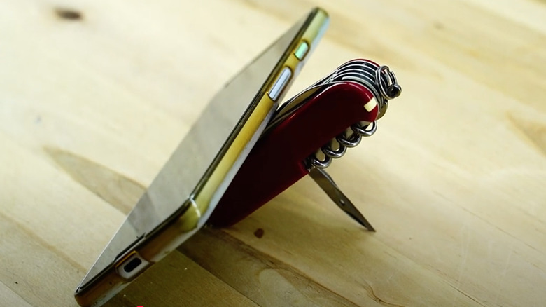 A mobile phone standing using Swiss Army Knife sewing awl