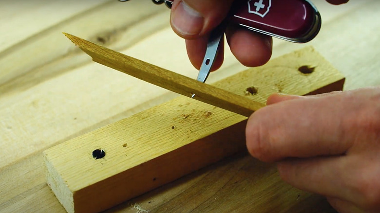 Person using Swiss Army Knife sewing awl to punch hole through a piece of wood