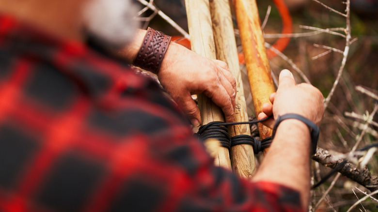 A man untying knots around sticks