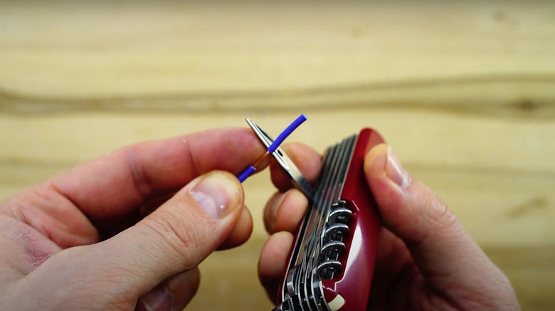 A man stripping wire with a Swiss Army Knife