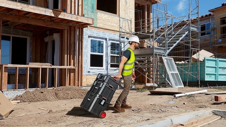 A person pulling a bauer modular rolling toolbox system on a construction site