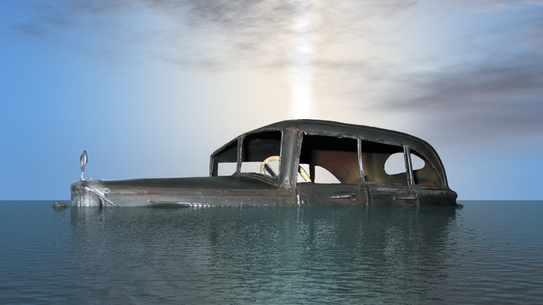 Vintage car half sunken in ocean