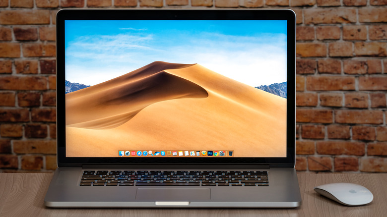 MackBook displaying desktop in front of brick wall backdrop