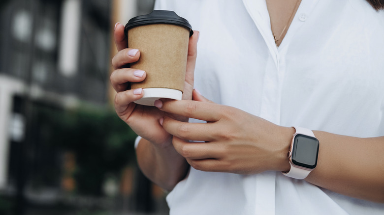 woman walking with coffee cup and Apple Watch