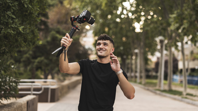 A man holding a camera with a flip screen while vlogging