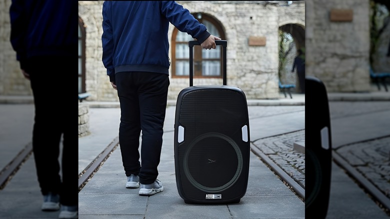 Person rolling their Altec Lansing SoundRover Bluetooth speaker down pavement