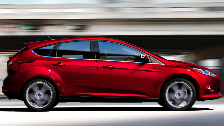 Passenger side view of red Ford Focus driving