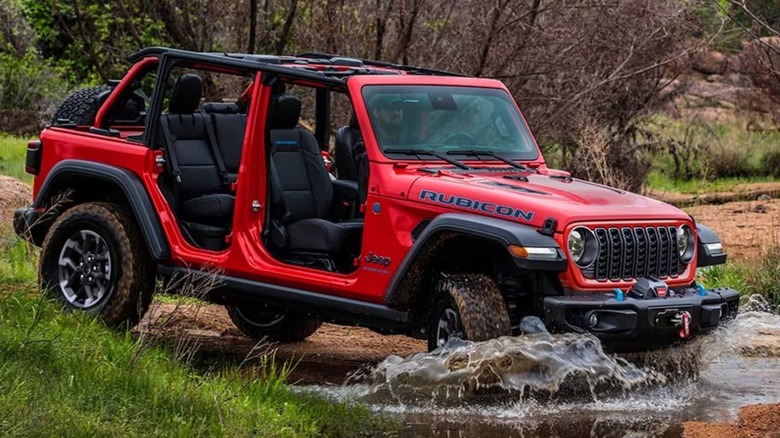 red 2025 Jeep Wrangler crossing a stream with no doors or top.