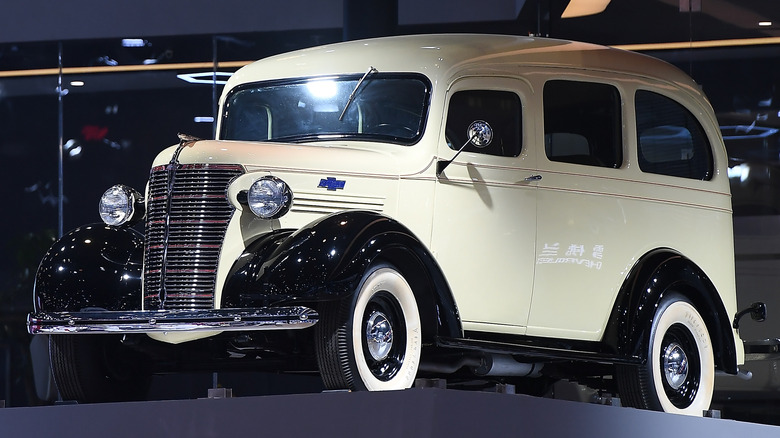 A white 1935 Chevrolet Suburban displayed at an auto exhibit