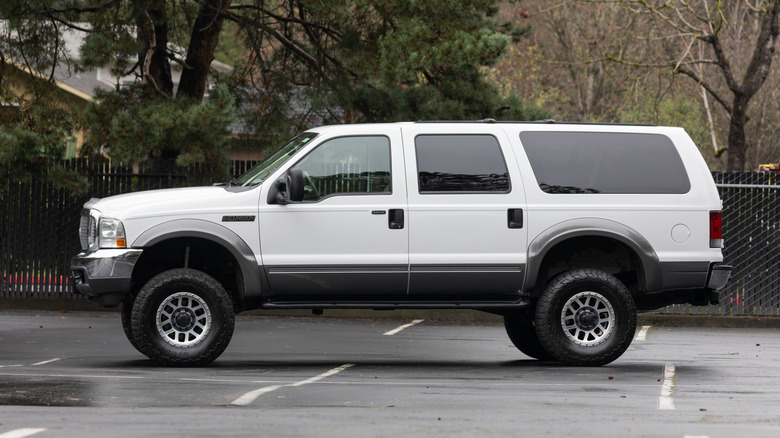 A white Ford Excursion in an empty parking lot