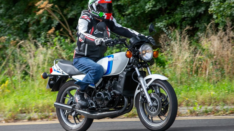 Man riding a 1980 white Yamaha RD350 motorcycle