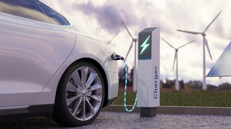 Windmills and solar panels charging an electric vehicle