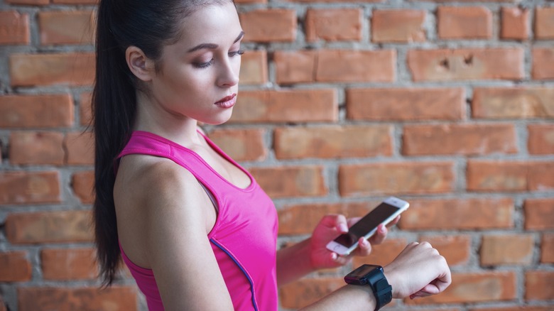 person holding smartphone with Fitbit