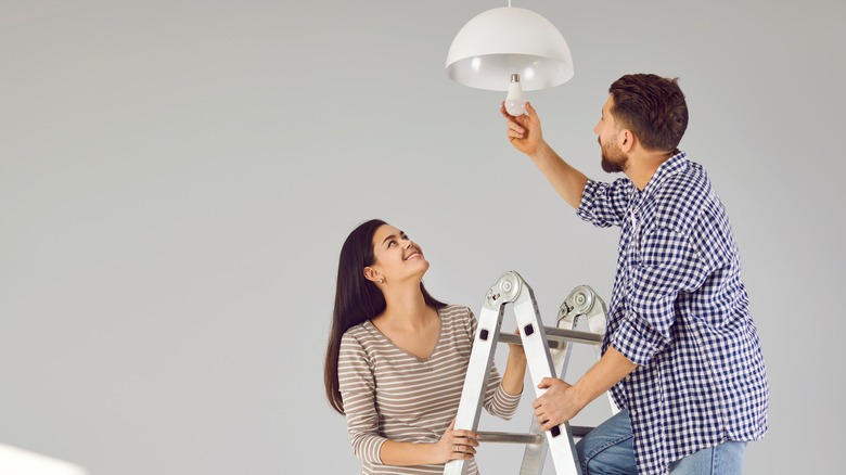 couple replacing a ceiling light