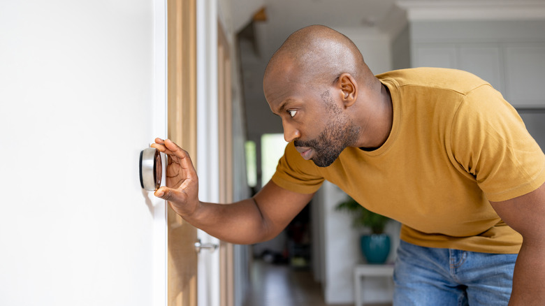 man adjusting thermostat