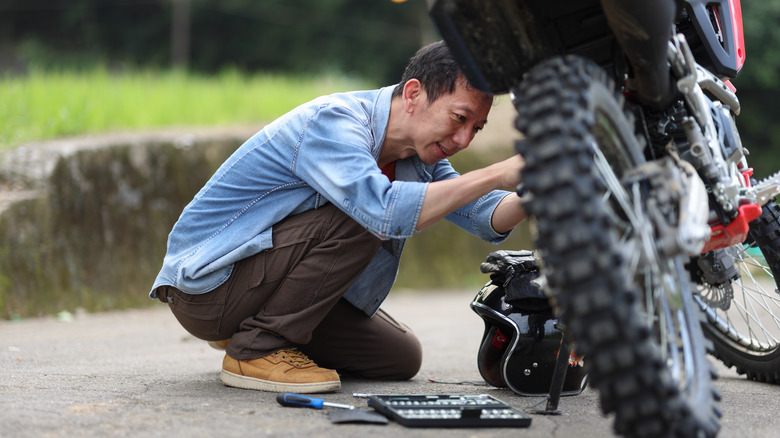 Man is troubleshooting a motorcycle problem