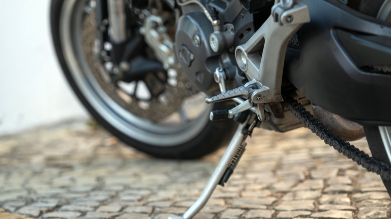 The kickstand of a motorcycle rests firmly on rustic cobblestones