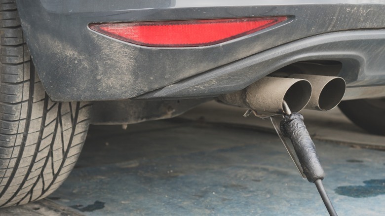 A car with an emissions testing tool attached to its exhaust pipe.