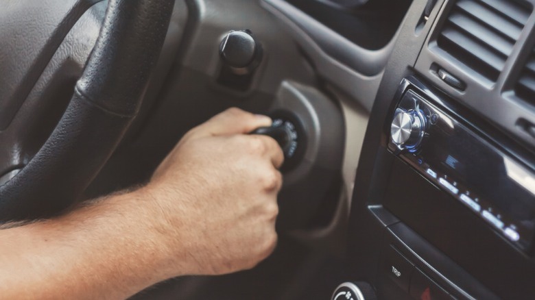 A person's hand turning a car ignition key.