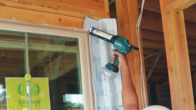 A person using Makita caulking gun to seal windows