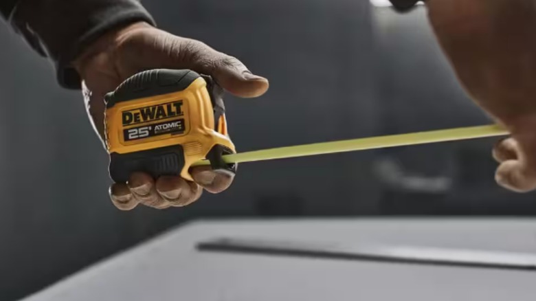 A person using the DeWalt ATOMIC 25-foot tape measure