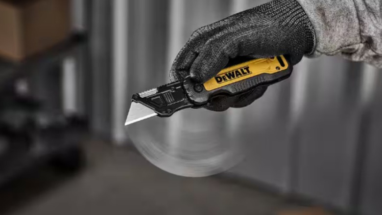 A gloved hand holding a DeWalt utility knife