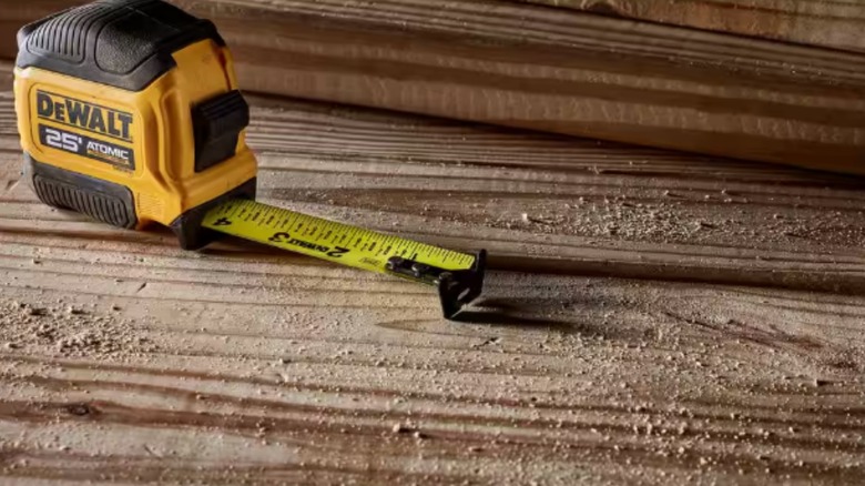 A DeWalt ATOMIC 25-foot tape measure sitting on a piece of lumber