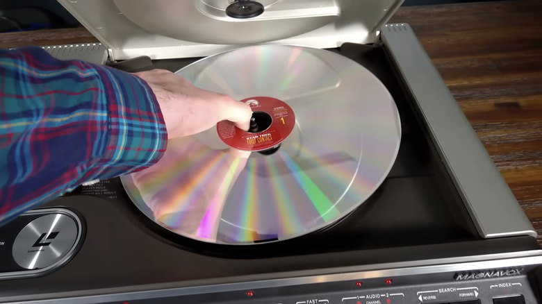 man's hand inserting Laserdisc in top-loading player